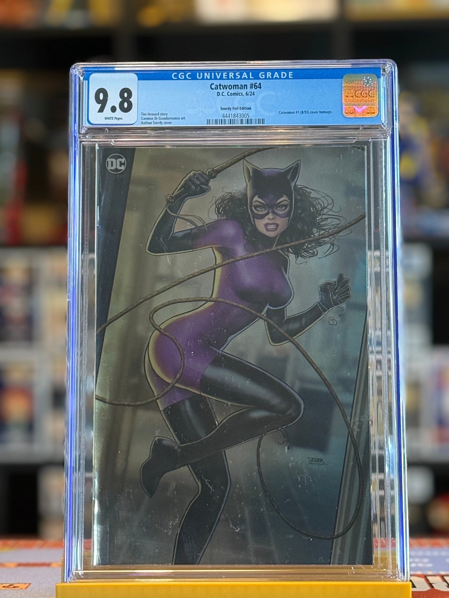 High-resolution image of Catwoman #64 CGC 9.8 featuring Nathan Szerdy’s Foil Virgin Variant cover. Artwork displays Catwoman, Poison Ivy, and Harley Quinn in a dynamic, modern foil-rendered design inside a clear CGC slab.